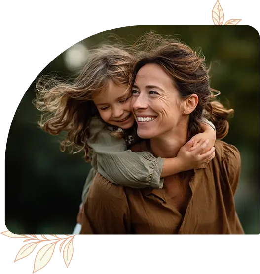 A mother smiling and embracing her child outdoors